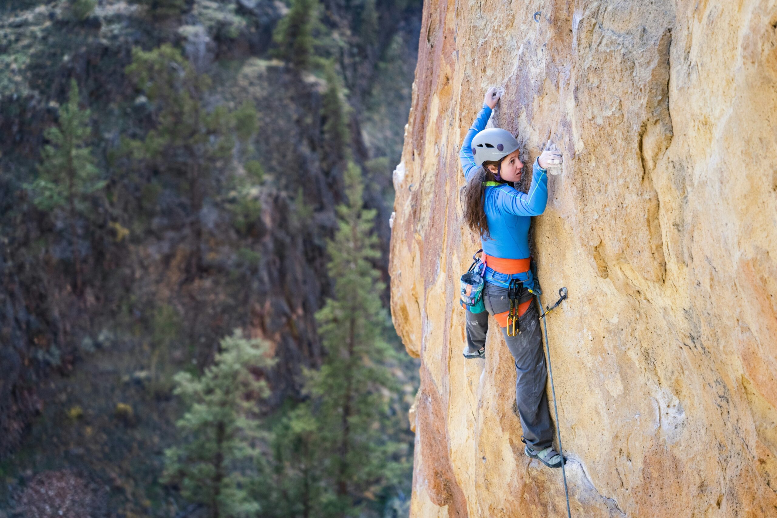 A climber adjusting their harness before ascending a rock wall