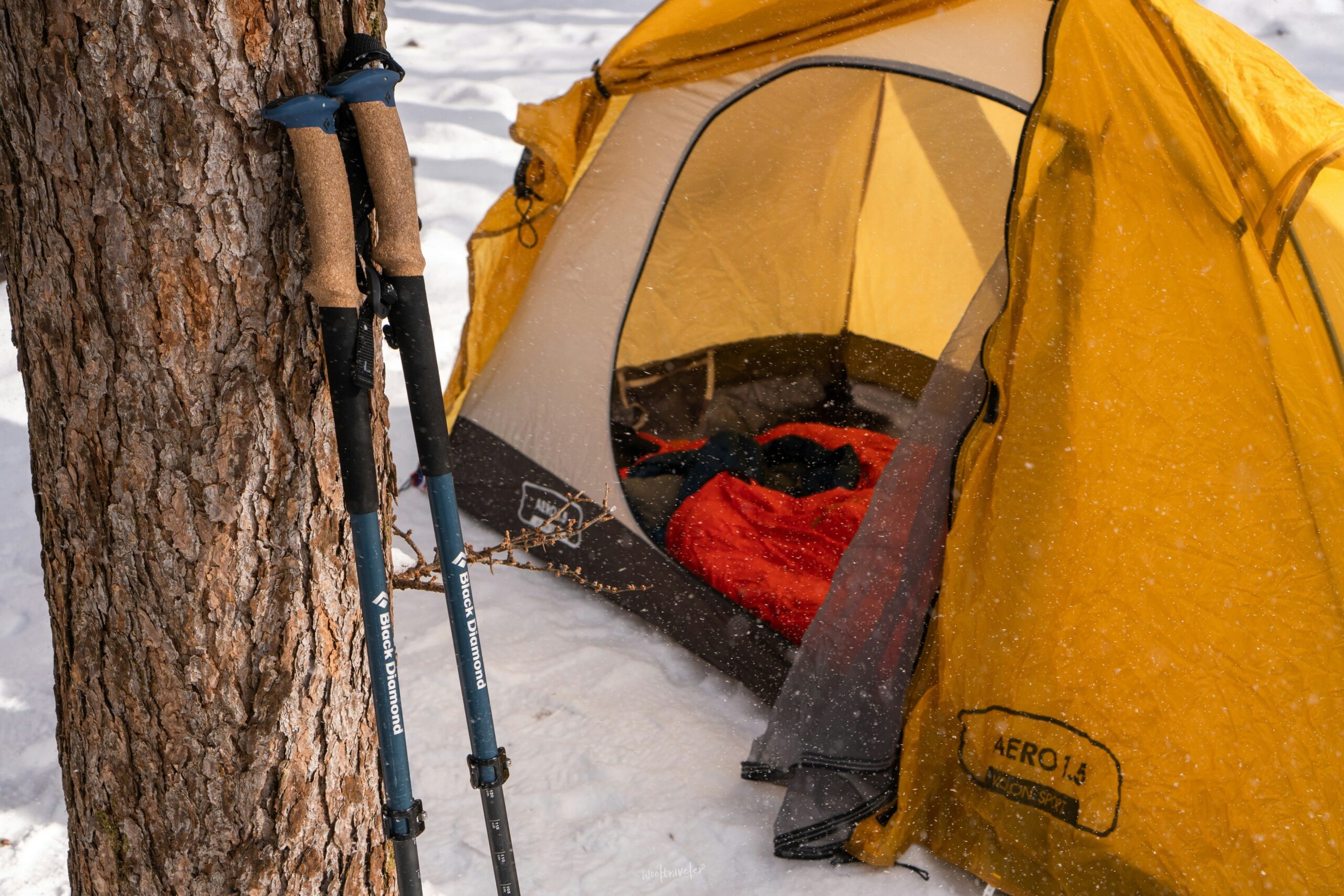 A climber standing next to their gear bag which contains a helmet, shoes, chalk, and harness