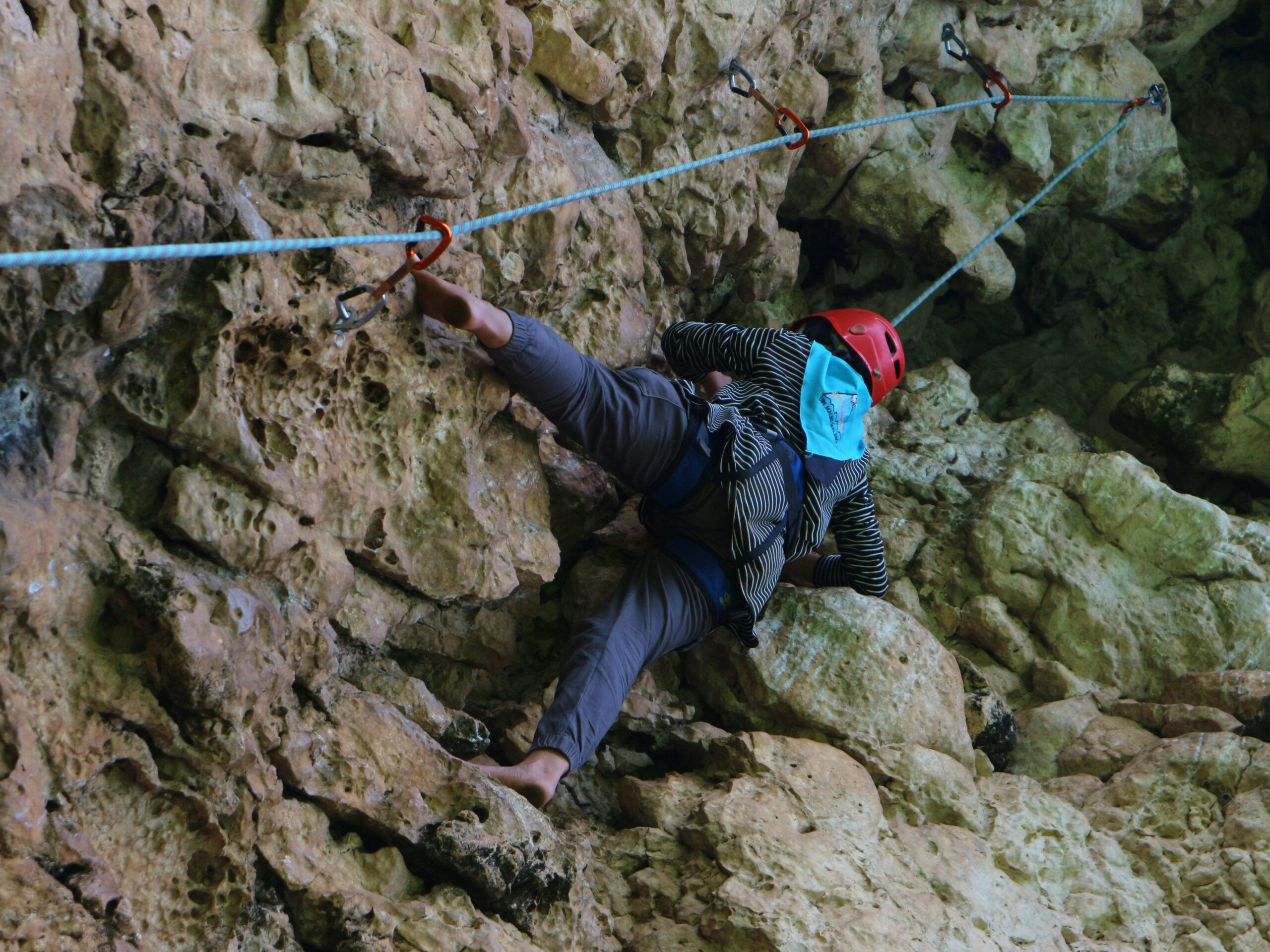 A man performing pull-ups using his climbing harness suspended from a bar