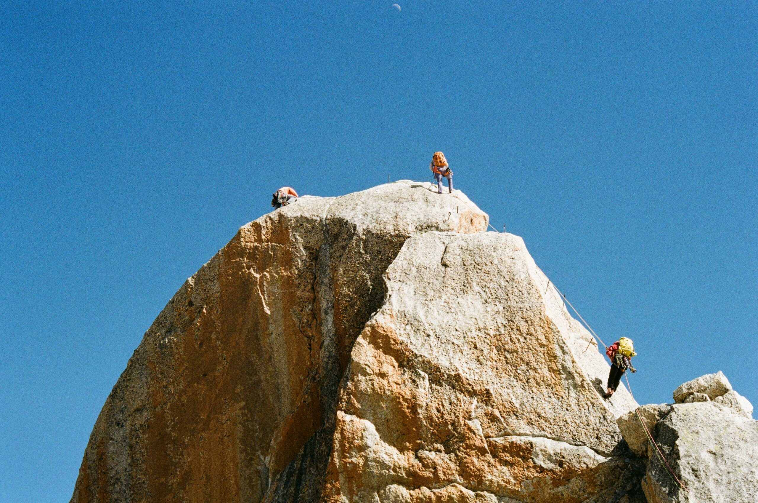 Two friends assisting each other while practicing rock climbing indoors