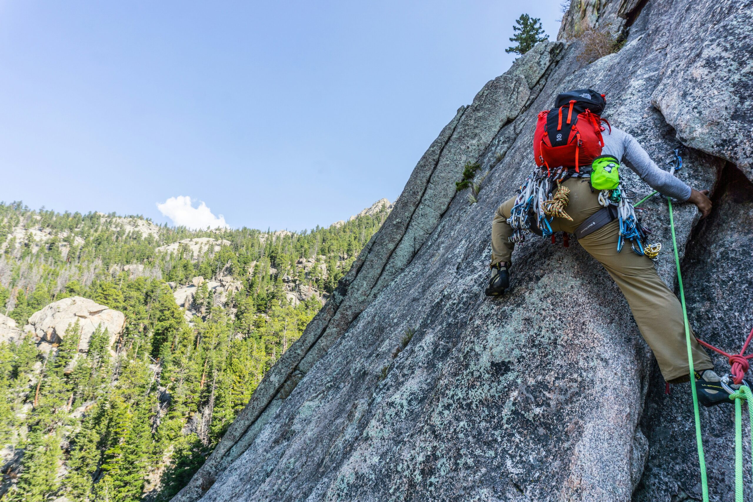 Smiling climber standing at the summit with arms raised