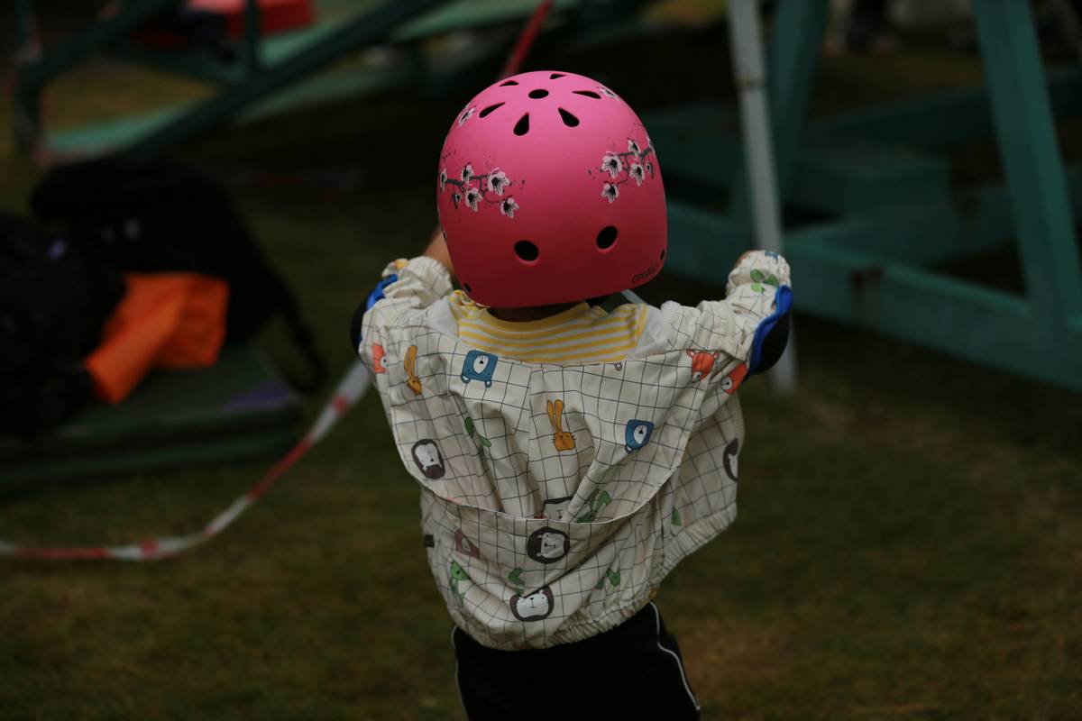 A young child wearing a secure climb harness while scaling a boulder.