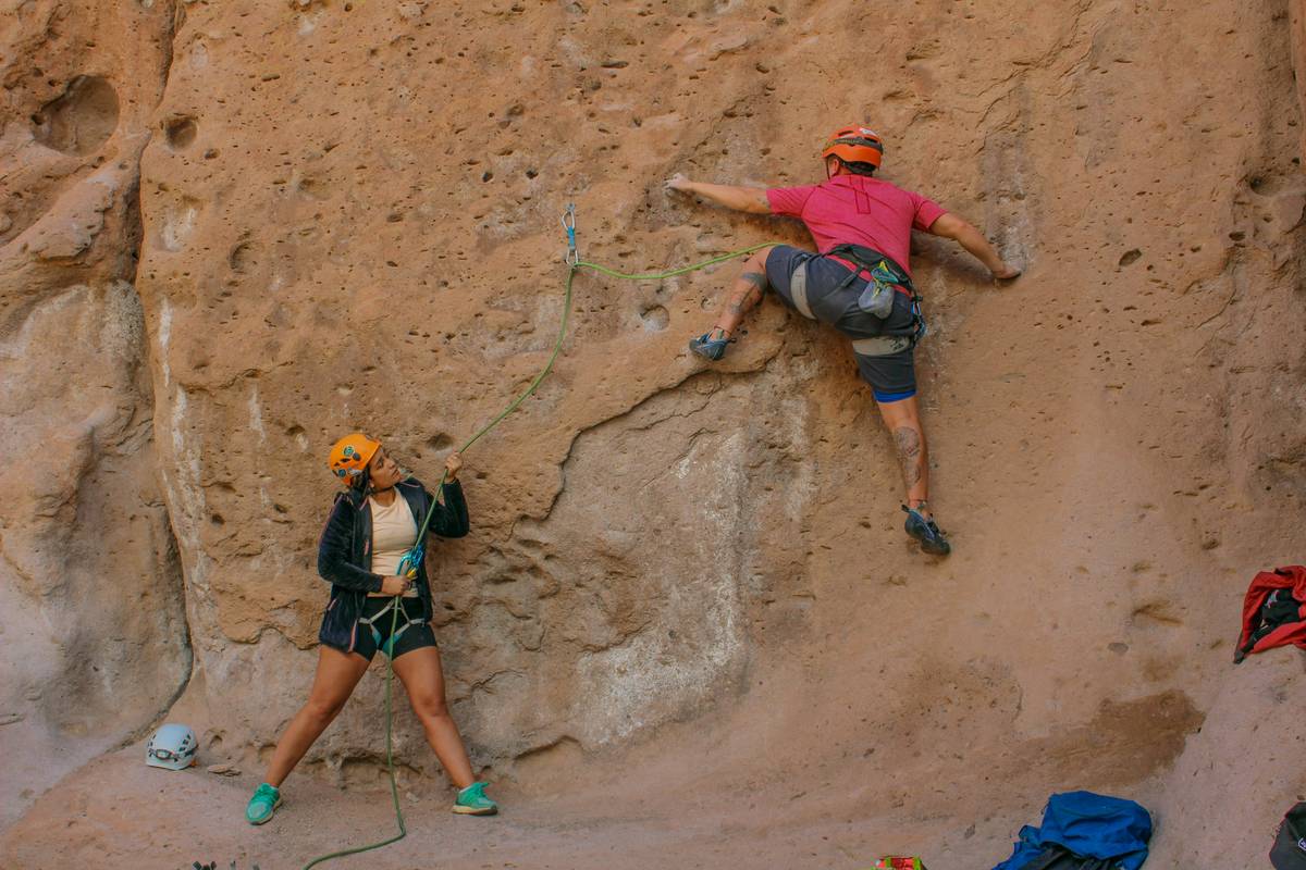 Two climbers checking each other's equipment before starting a climb.
