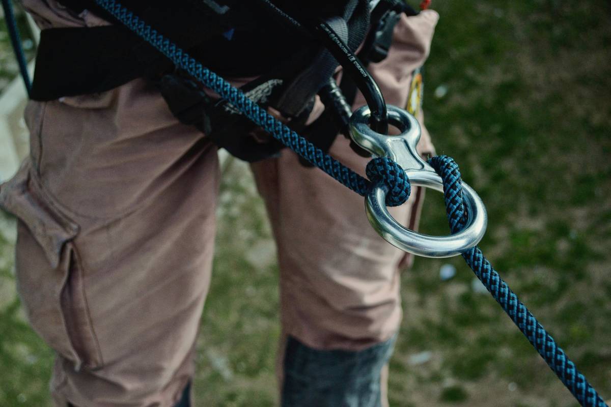 A short climber confidently scaling a rock face with a well-fitted harness.