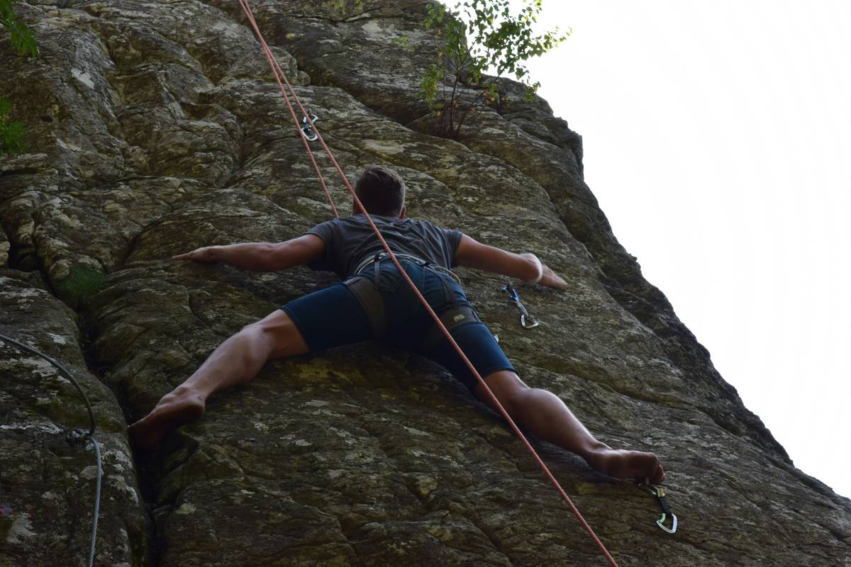 Tall climber smiling confidently near a cliff edge